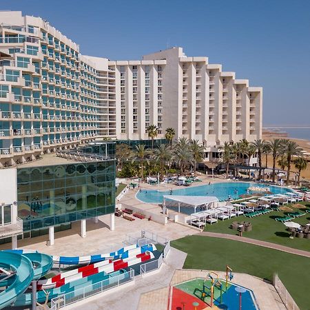 Leonardo Club Hotel Dead Sea - All Inclusive Neve Zohar Exterior foto The image shows a large hotel complex alongside a pool area. The hotel features modern architecture with multiple levels and numerous balconies. In front of the hotel, there is a recreational area with a swimming pool, water slides, and lounging chai