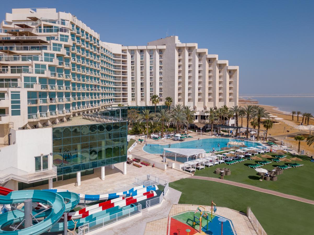 Leonardo Club Hotel Dead Sea - All Inclusive Neve Zohar Exterior foto The image shows a large hotel complex alongside a pool area. The hotel features modern architecture with multiple levels and numerous balconies. In front of the hotel, there is a recreational area with a swimming pool, water slides, and lounging chai
